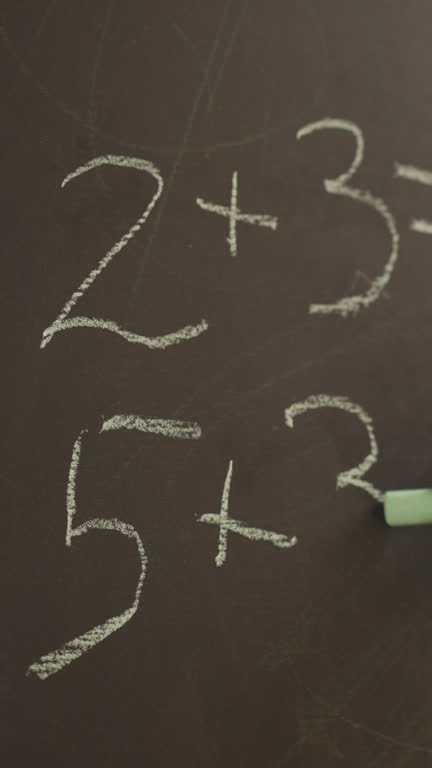 Schoolgirl writes mathematical examples on blackboard