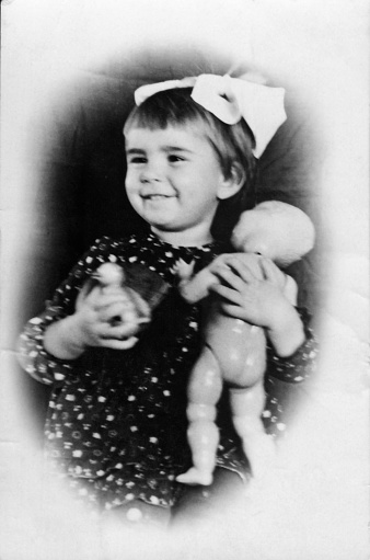 Vintage photo of a little girl holding a doll. USSR, circa 1945. Retro.