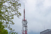 cell phone and television tower against the background of a building and trees, view from below from the ground