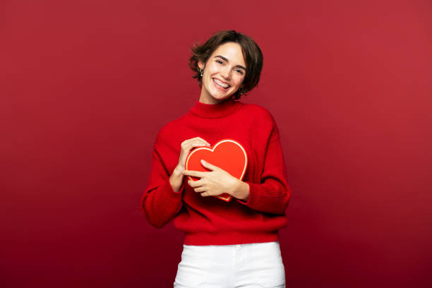 istock Beautiful young woman smiles at camera, while holding out a red gift box, isolated 2149714940
