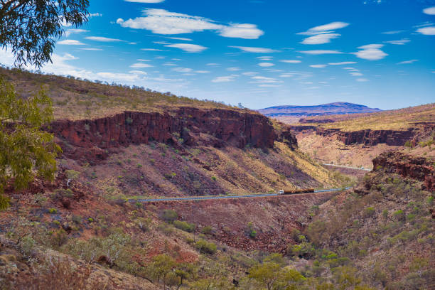 Road train on the Great Northern Highway, Western Australia, in a spectacular gorge Road train on the Great Northern Highway in Karijini National Park, Western Australia. The highway winds through a spectacular canyon barron gorge national park stock pictures, royalty-free photos & images
