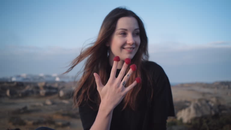 Smiling girl eats raspberries of fingers