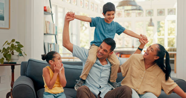 istock Love, happy family and airplane fun on a sofa with care, security and support while bonding at home. Flying, balance and excited kids with parents in a living room for playing shoulder games together 2149715352