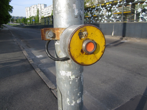 Grungy rusty red pedestrian crosswalk traffic light button, residential district city street.