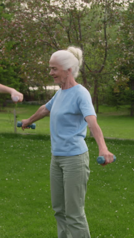 Senior Caucasian Woman Participating in Exercise Class with Dumbbells in Park