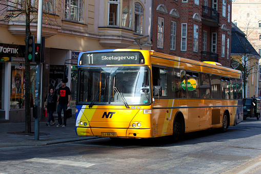Aalborg, Denmark. October 1, 2011. Yellow bus with number 11 and Skelagervej signage moving on street with residential buildings in background in city during sunny day