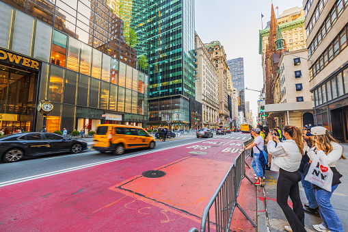 NY. USA. 04.15.2024. Beautiful view of the vibrant street scene in front of Trump Tower on New York's 5th Avenue, capturing the essence of urban life with pedestrians and iconic yellow cabs.