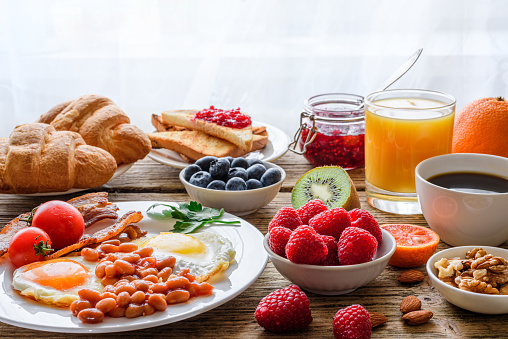 Breakfast buffet. Full english and continental breakfast. Large selection of brunch food on the table with egg, bacon, toast, orange juice, croissant, coffee, fruits and nuts.