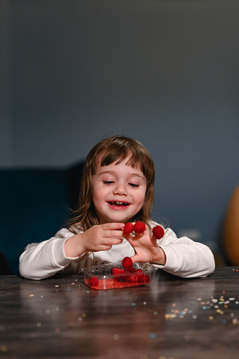 little preschool girl eating fresh raspberries