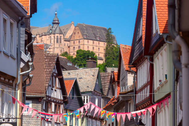 Traditional timber-framed houses line the cobblestone street leading to Marburg Castle, Germany