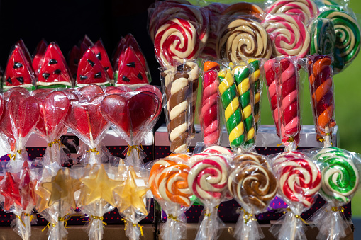 Various lollipops, including heart-shaped and watermelon, displayed for sale.