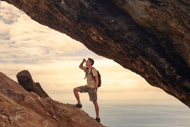 Man  climbing up mountain looking up at the challenge before him. Believe in yourself, overcoming challenges, pushing forward concept.