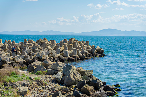 Sea landscape with concrete tetrapod breakwater stones piled up in wave breaker to protect, natural background