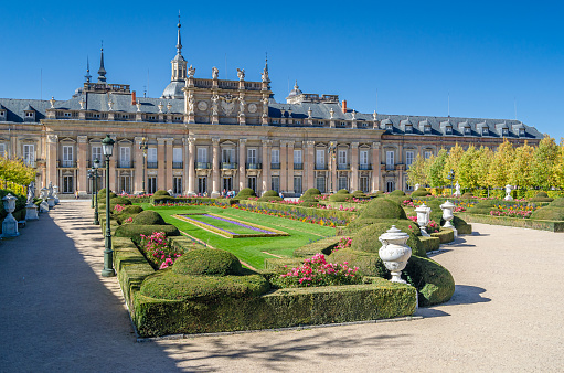Real Sitio de San Ildefonso, Spain - October 13, 2019: Gardens in the French formal garden style with sculptural fountains and the Royal Palace of La Granja de San Ildefonso in the background, an 18th-century palace in the town of San Ildefonso, Spain