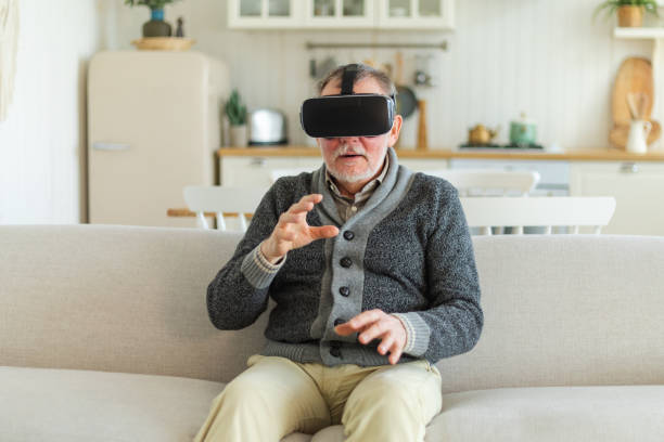 istock Excited mature senior man wearing using virtual reality metaverse VR glasses headset at home. Grandfather touching air during VR experience on virtual reality helmet. Simulation hi-tech videogame. 2149739020
