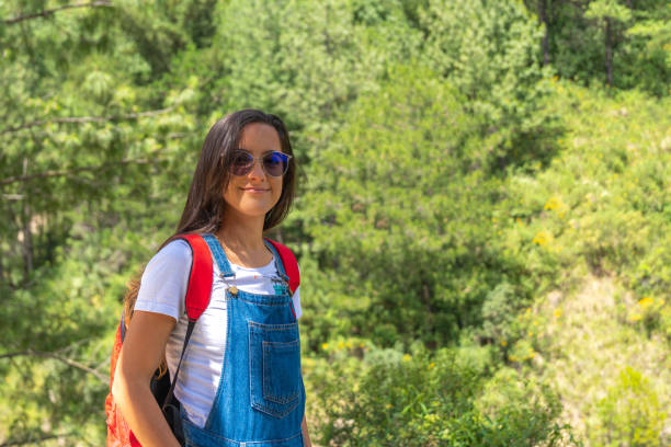 Young woman looking at the horizon with her hands on her hips, from the top of a mountain.
