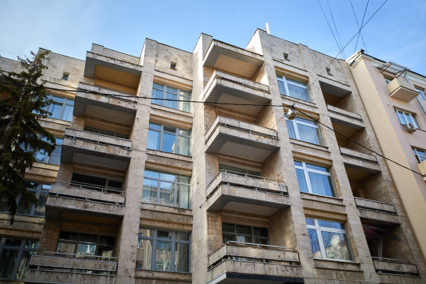 High angle view of a modern residential multistory building with large balconies and windows against blue sky.
