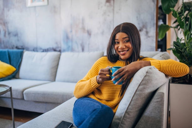 istock Woman with phone and cup on a comfy sofa 2149742472