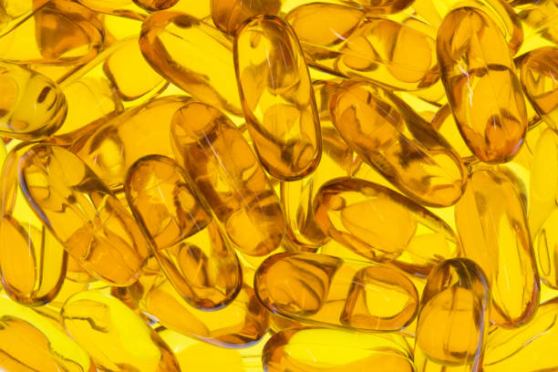 Omega 3 krill fish oil capsules supplements backlit scattered.