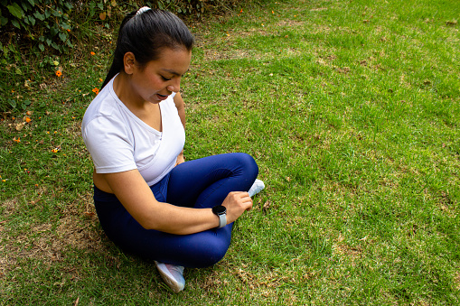 Young woman exercising in a park and watching smart watch