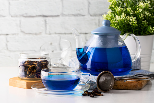 Organic blue tea. glass and teapot on the white table. Herbal beverage