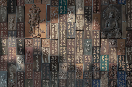 Bangkok, Thailand - Apr 11, 2024 - Chinese lettering teachings and Carved buddha images into a slab of colored tiles on temple wall of Fo Guang Shan Thaihua Temple. Taiwanese temple style, Space for text, Selective focus.