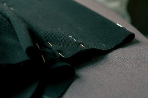 close-up in a sewing workshop a seamstress pinned black fabric for corrugation