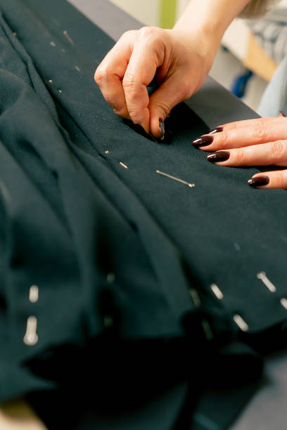 istock close up in a sewing workshop a seamstress pins a corrugated pin on a black fabric 2149748068