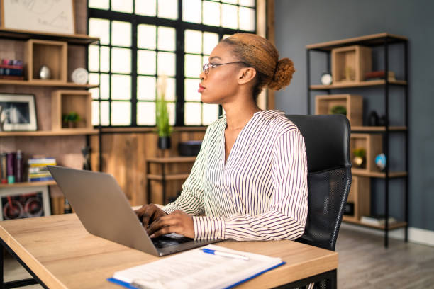 istock Female office worker looking into the distance for inspiration, with her hands touching a laptop keyboard 2149748152