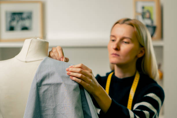 istock in sewing workshop seamstress works with a mannequin and pins blue fabric with a pin 2149749952