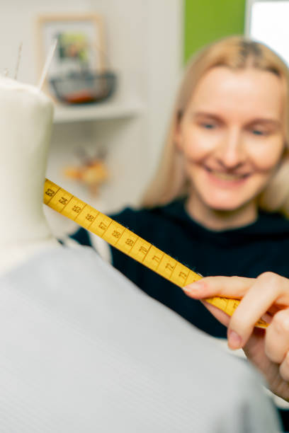 close up in a sewing workshop a seamstress works with a mannequin on a blue fabric measures with a centimeter