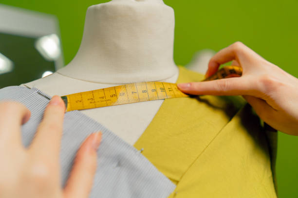 istock close up in a sewing workshop seamstress works with a mannequin on a blue fabric measures with a centimeter 2149750734