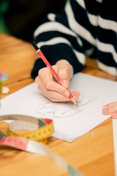 istock close-up in a sewing workshop woman's hand draws a sketch of future clothes 2149751150