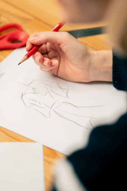 istock close-up in a sewing workshop woman's hand draws a sketch of future clothes 2149751212