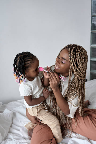 istock Joyful black happy woman applying makeup on her daughter's face 2149751314