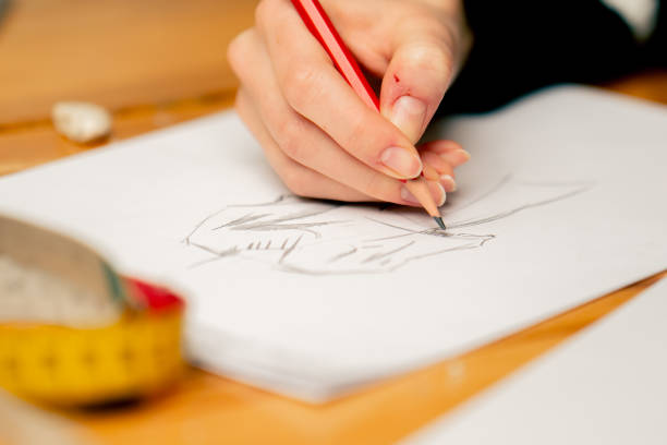 istock close-up in a sewing workshop woman's hand draws a sketch of future clothes 2149751375