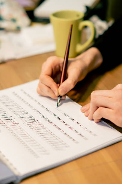 istock close-up in sewing workshop the artist s hands are doing calligraphy in a notebook 2149751811