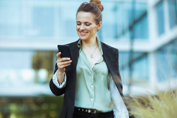 istock happy woman worker near office building using phone and walking 2149753189