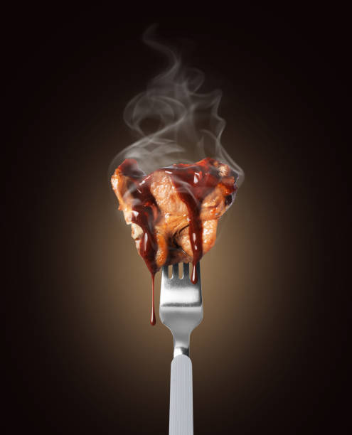istock Hot fried beef steak poured with sauce on a fork close up on a black background 2149753294