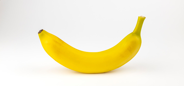 One yellow banana on a white background. The concept of taking vitamins in the summer