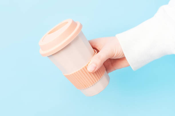 istock Female hand hold ceramic glass with coffee on blue background, side view. 2149757078