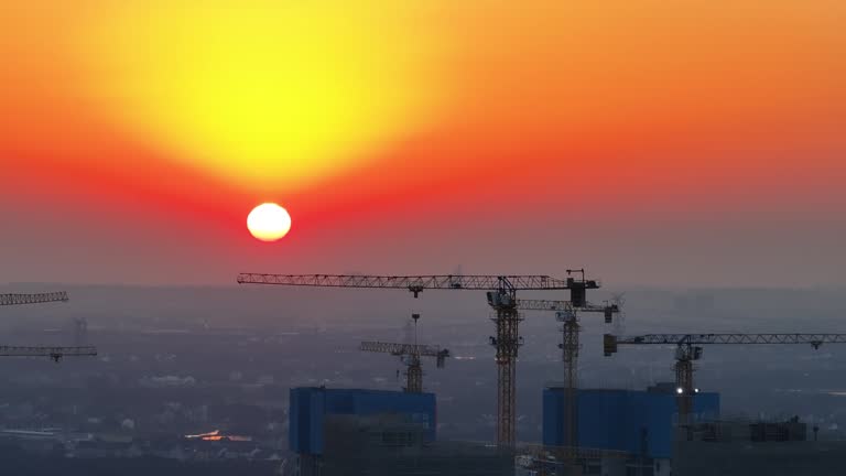 Industrial construction cranes and building silhouettes over sun at sunrise.Pudong, Shanghai