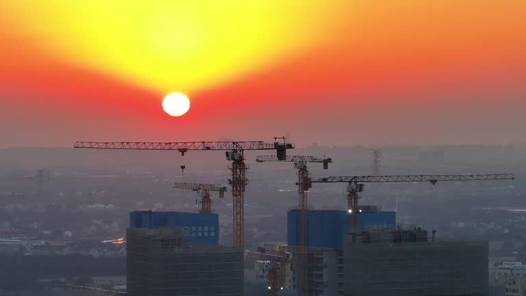 Industrial construction cranes and building silhouettes over sun at sunrise.Pudong, Shanghai