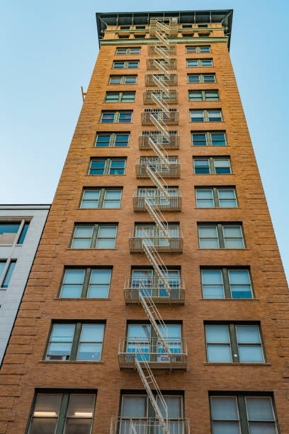istock Tall brick building with external fire escape against a clear blue sky. 2149758452