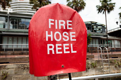 Fire hose reel outdoors with a red cover.