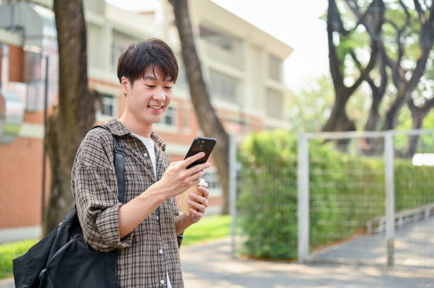 istock A handsome, positive young Asian man in casual wear using his smartphone while walking in a park. 2149759037