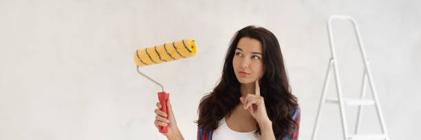 istock Thinking Painter Woman Portrait With Paint Roller on Unpainted Wall 2149759145