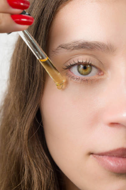 istock Happy young woman applying serum on her face with her eyes open. 2149759497
