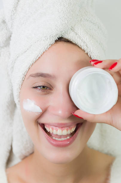 istock Happy young woman applying serum on her face with her eyes open. 2149759545