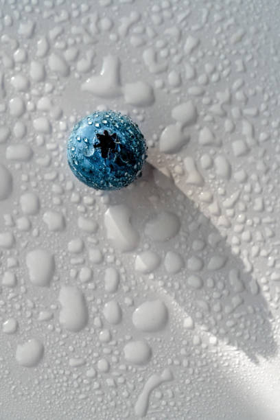 A close up of a blue sphere with many small droplets of water on it. Concept of calmness and tranquility, as the water droplets seem to be suspended in mid-air, creating a serene atmosphere